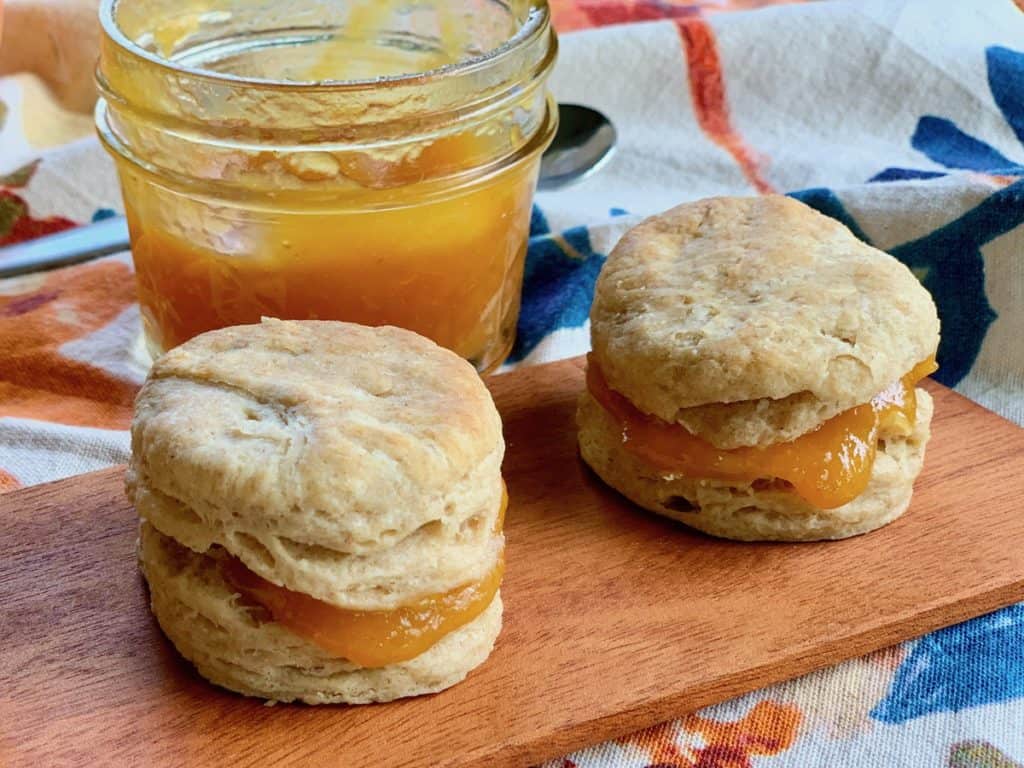 Two Small Biscuits sliced and filled with Peach Butter from a small mason jar.