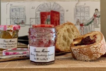 Several jars of fruit spreads on a wooden cutting board with slices of Sourdough Bread with a Bonne Mama advent calendar in the background.