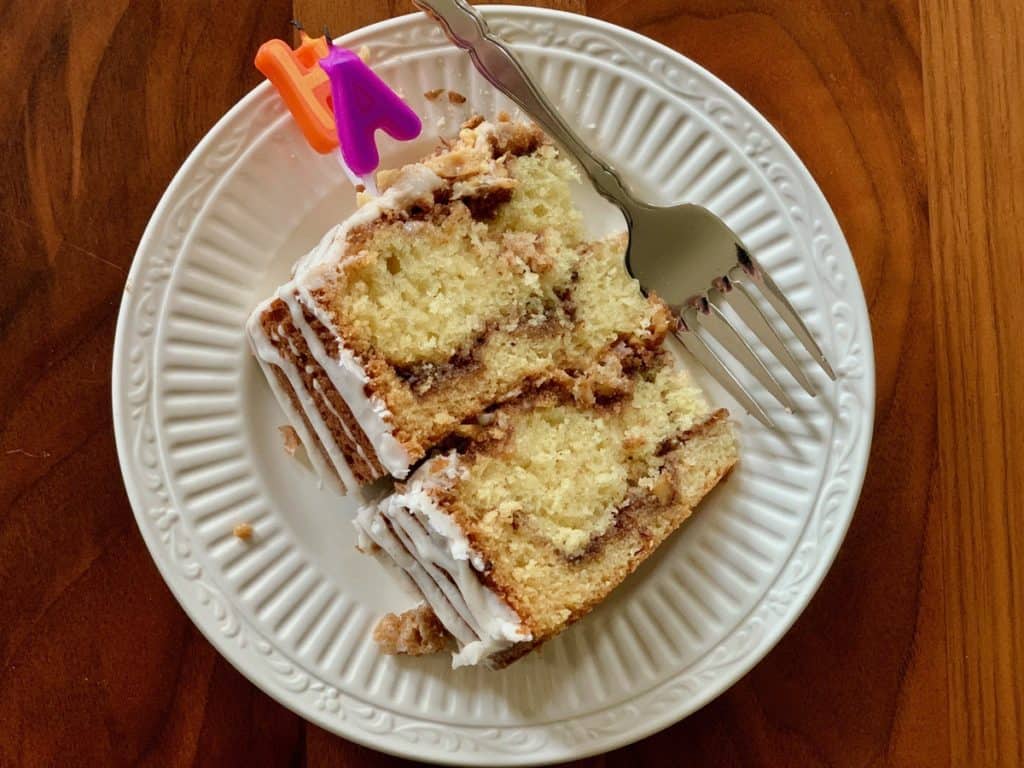 A slice of Cinnamon Sour Cream Layer Cake with birthday candles on top.