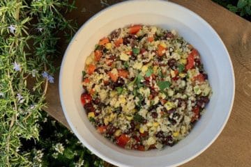 Southwest Quinoa Salad, with black beans, corn, red pepper and cilantro, in a white serving dish in the garden.