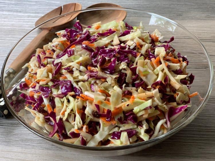 Slimmer Cole Slaw in a glass bowl with wooden serving spoons.