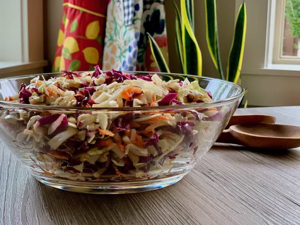 Slimmer Slaw, made with purple cabbage, carrots and cranberries, served in a glass bowl.