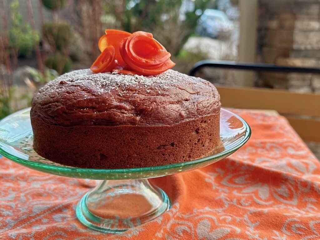 Wild Persimmon Cake topped with persimmon flowers and served on a green cake plate.