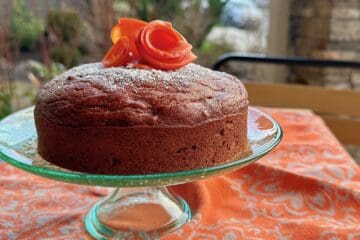 Wild Persimmon Cake topped with persimmon flowers and served on a green cake plate.