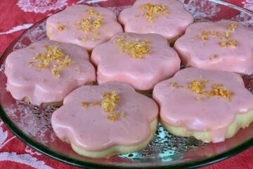 Compari Iced Shortbread Cookies are topped with Golden Orange Sugar and arranged on a green glass cake stand.