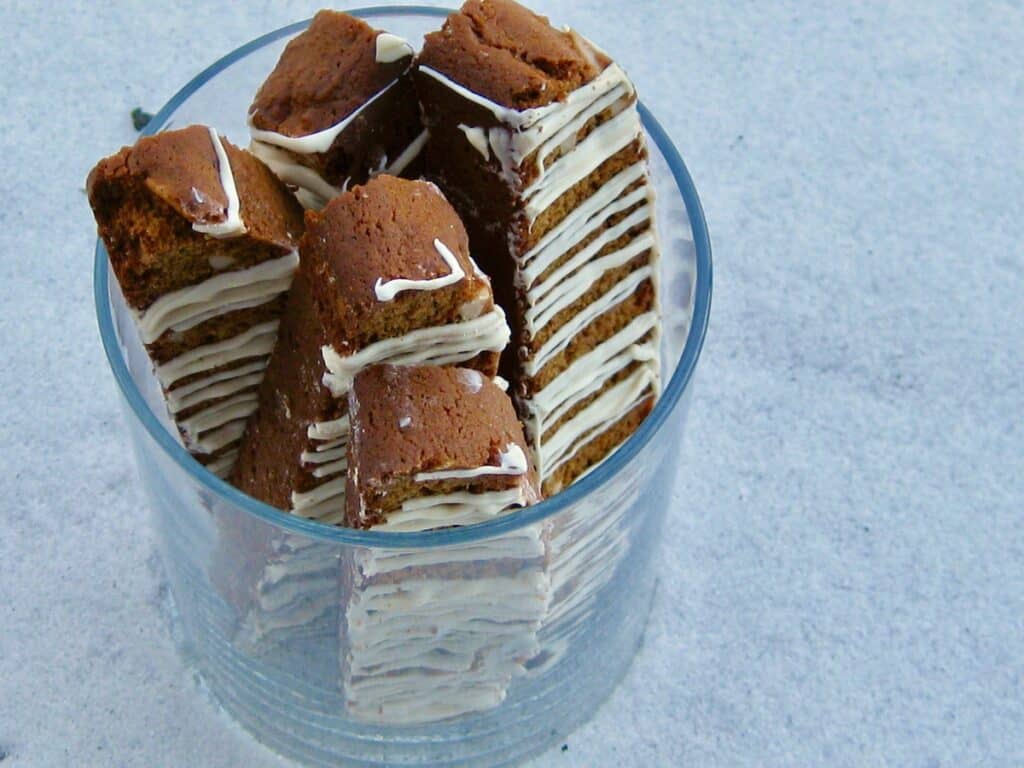 Gingerbread Biscotti arranged in a glass on a snowy background.