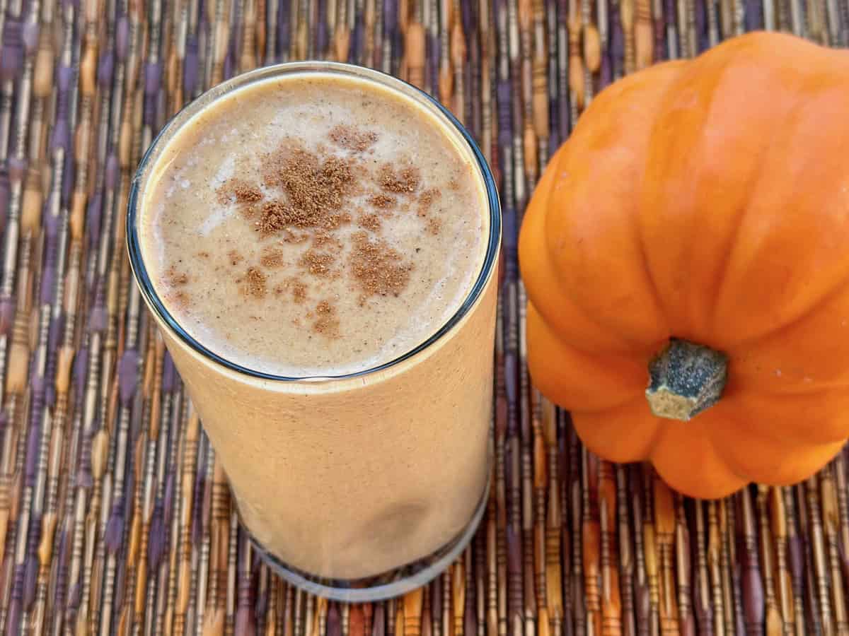 A Pumpkin Pie Protein Shake in a glass with a sprinkle of Pumpkin Pie Spice on top.