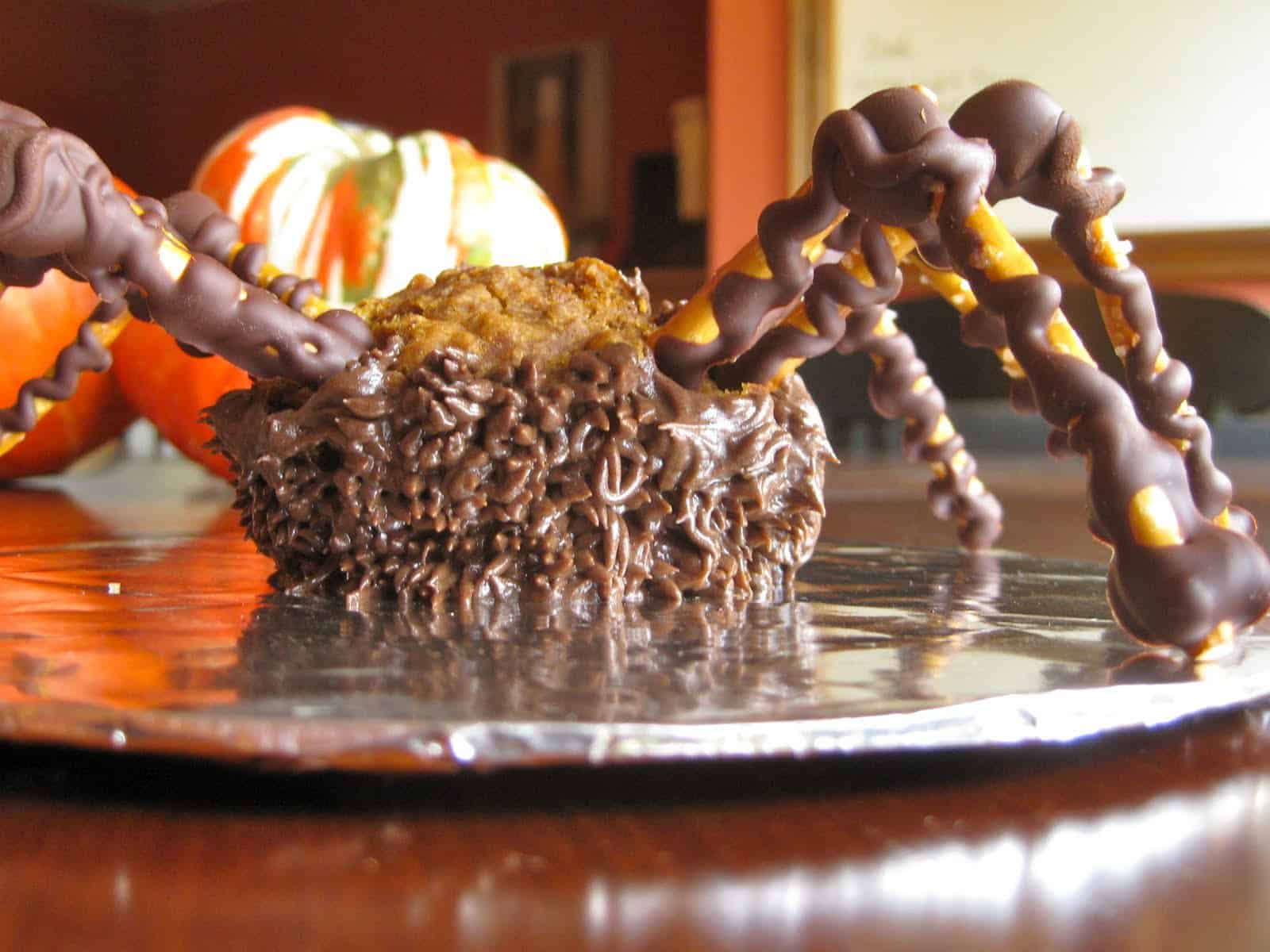 An unfinished Spider Cupcake with missing buttercream but with pretzel legs attached.