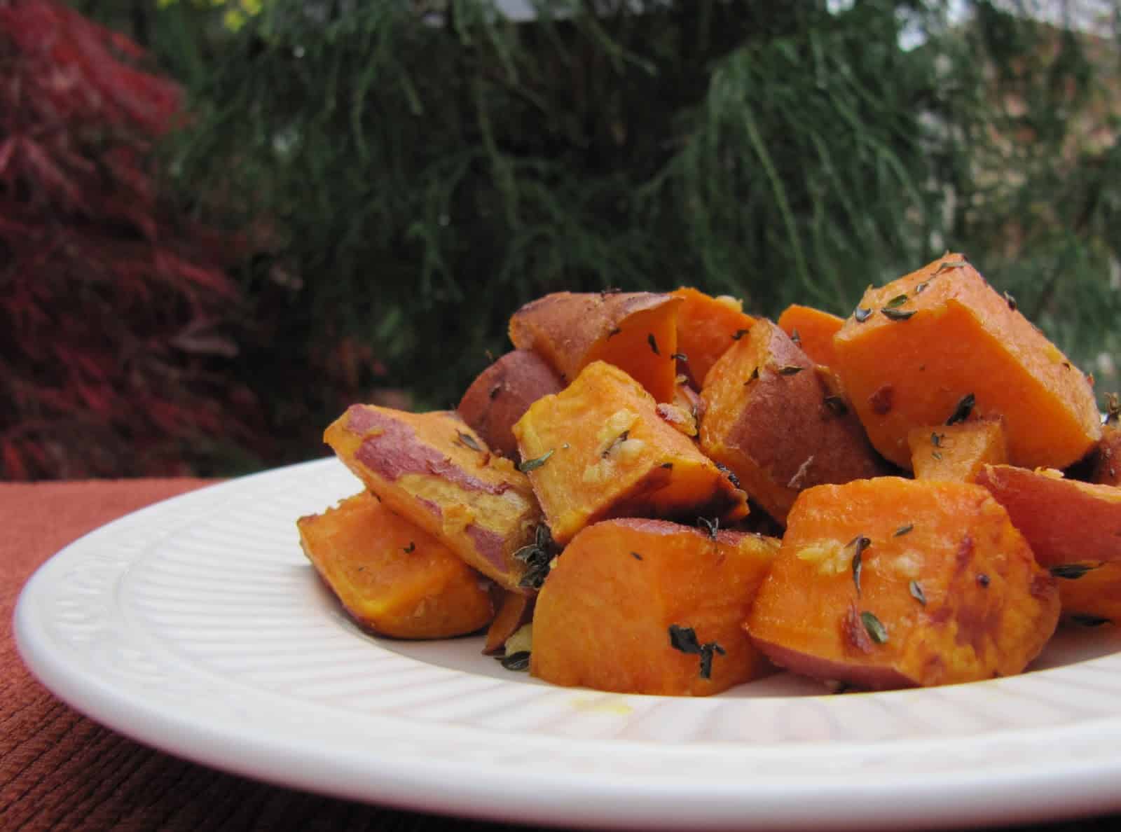 A serving of Thyme Roasted Sweet Potatoes on a white plate.