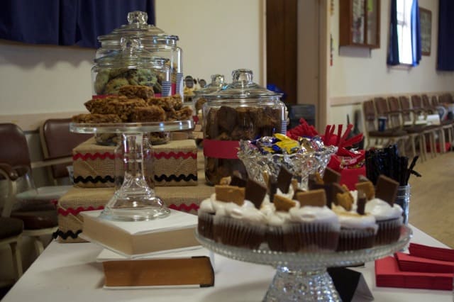 Dessert table decorations including jars of cookies, covered book risers and candy