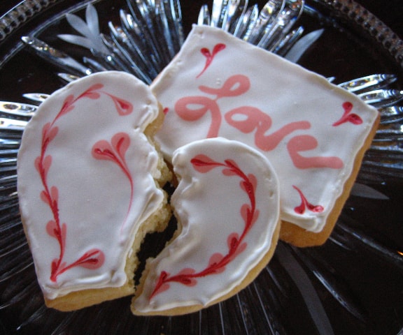 Sugar Cookies with decorated Royal Icing in the shape of a broken heart and a "Love" inscribed rectangle, served on a crystal platter.